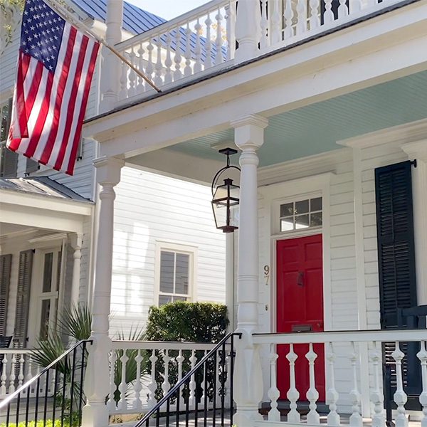 A light blue home with a red door and an American flag